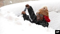 Zaria Black, 24, , clears off her car as snow falls in Buffalo, N.Y. 