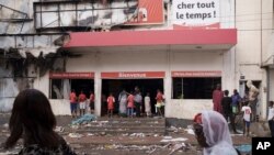 People stand at the entrance of a destroyed supermarket in Dakar, Senegal, June 3, 2023.