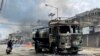 Seorang pengendara motor melewati truk tangki air yang dibakar massa di tengah bentrokan maut antaretnis di Churachandpur di negara bagian timur laut Manipur, 4 Mei 2023. (Foto: Reuters)