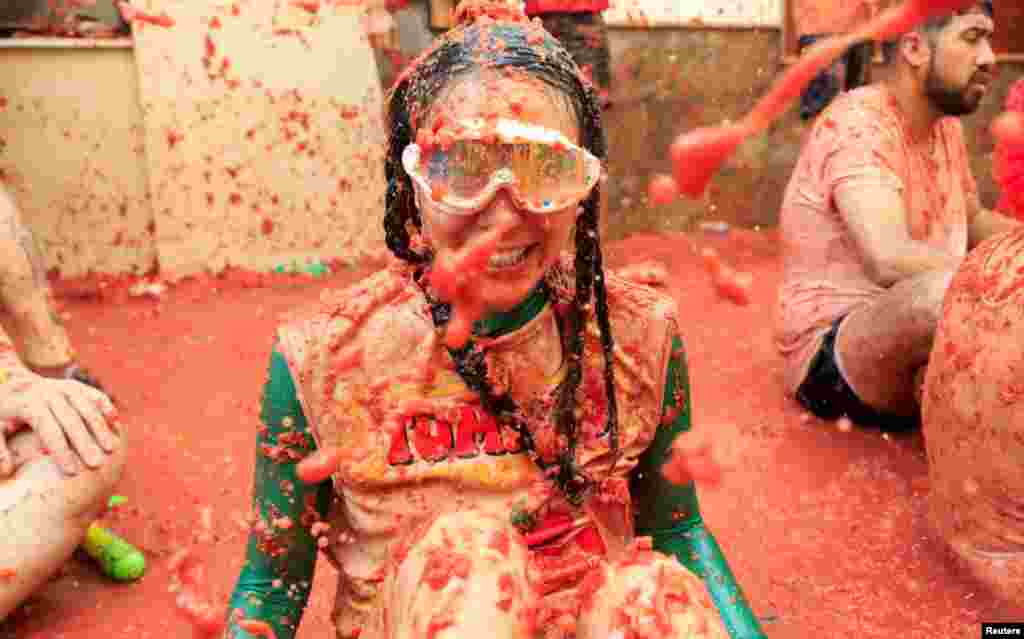 Una participante cubierta de pulpa de tomate observa mientras la gente asiste al festival anual de lucha contra la comida "La Tomatina" en Buñol, cerca de Valencia, España. 