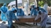 Petugas kesehatan dan kerabat membawa jenazah korban COVID-19 untuk dikremasi di Jammu, India, Minggu, 25 April 2021. (Foto: AP)