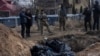 На фото: Люди стоять біля братської могили в Бучі, на околиці Києва, Україна, понеділок, 4 квітня 2022 року. (AP Photo/Rodrigo Abd)
