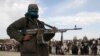 FILE - A member of the Taliban insurgent and other people stand at the site during the execution of three men in Ghazni Province, Afghanistan, April 18, 2015. 