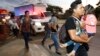 Decenas de migrantes que buscan llegar a Estados Unidos caminan por una carretera mientras salen de San Pedro Sula, Honduras, al amanecer del martes.