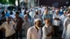 In this Aug. 13, 2016, photo, people gather near a crime scene for a demonstration after the leader of a New York City mosque and an associate were fatally shot in a brazen daylight attack as they left afternoon prayers Saturday. 