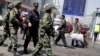 FILE - Armed Chinese paramilitary policemen march past the site of an explosion outside the Urumqi South Railway Station in Urumqi in northwest China's Xinjiang Uygur Autonomous Region, May 1, 2014.