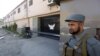 An Afghan policeman guards the gate of a guesthouse after an attack the previous night in which 14 civilians were killed, in Kabul, May 14, 2015. 