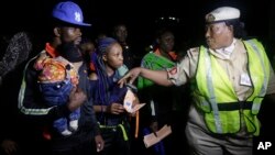 FILE - An unidentified Immigration officer, right, speaks to Nigerian returnees from Libya upon arrival at the Murtala Muhammed International Airport in Lagos Nigeria, Dec. 5, 2017. 