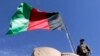 FILE - An Afghan National Directorate of Security (NDS) police stands guard next to an Afghanistan flag at a guard post of a police camp in Now Zad district in Helmand province, Afghanistan.