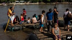 FILE - Rafts loaded with passengers leave Tecun Uman, Guatemala, to cross the Suchiate River to reach Mexico, June 25, 2019.