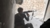 FILE - An Islamic State fighter aims his rifle in Kobani, Syria.