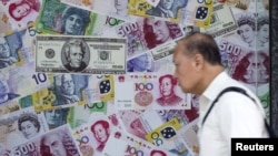 中国香港，一名男子经过一家外汇商店的广告，该广告宣传人民币、美元和欧元兑换服务。