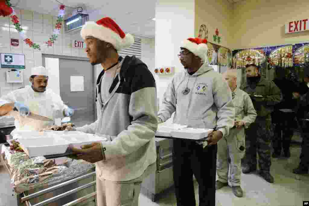Civilians in Santa Claus hats and service members with the NATO-led International Security Assistance Force wait to be served Christmas dinner at the U.S.-led coalition base in Kabul, Afghanistan, December 25, 2012.