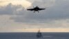 An F/A-18F Super Hornet from the Diamondbacks of Strike Fighter Squadron (VFA) 102, top, approaches to land on the flight deck of the aircraft carrier USS George Washington (CVN 73) while the Ticonderoga-class guided-missile cruiser USS Antietam (CG 54) t