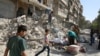 People remove belongings from a damaged site after an air strike Sunday in the rebel-held besieged Qaterji neighborhood of Aleppo, Syria, Oct. 17, 2016. 