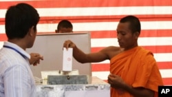 Cambodian Buddhist monk, right, casts his ballot in local elections at Wat Than pagoda's polling station in Phnom Penh, Sunday, June 3, 2012. 