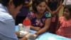 FILE - A public health worker takes a blood sample from a woman to be tested for malaria in Bo Rai district, Trat provice, Thailand.