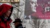 People pass by a pre-election poster of Ukrainian President and presidential candidate Petro Poroshenko in central Kyiv, March 25, 2019. 