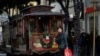 Una mujer lleva una bolsa de compras mientras camina frente a un tranvía en San Francisco, el viernes 29 de noviembre de 2019. (Foto AP/Jeff Chiu).