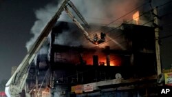 Kebakaran melanda sebuah gedung berlantai empat di dekat stasiun kereta api di pinggiran barat negara bagian Delhi, India Jumat (13/5). 