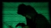 Un hacker encapuchonné tient un ordinateur portable alors qu'un cybercode est projeté sur lui. Cette photo d'illustration a été prise le 13 mai 2017. (Photo Reuters/Kacper Pempel)