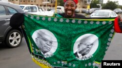 A supporter holds a flag depicting President Jacob Zuma during celebrations as delegates to the National Conference of the ruling African National Congress vote for their leadership in Bloemfontein, December 17, 2012. 