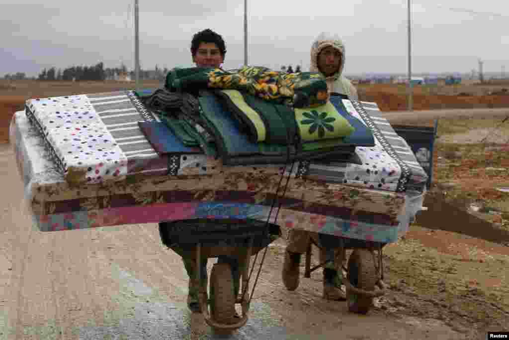 Syrian refugees transport their belongings after heavy rain at the Al Zaatari refugee camp in the Jordanian city of Mafraq, Dec. 12, 2013.