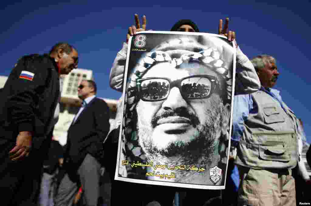A man holds a poster depicting late Palestinian leader Yasser Arafat during a rally in Bethlehem, ocupied West Bank, November 29, 2012. 
