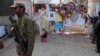 A soldier stands near a woman reading messages left by people for the victims of the Taliban attack on a school, in Peshawar, Pakistan, Dec. 23, 2014. 