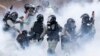 Police in riot gear move through a cloud of smoke as they detain a protester at the Hong Kong Polytechnic University.