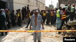 An injured man walks away as rescue workers search after a blast near the home of the home minister of Punjab province, Shuja Khanzada, in Attock, Pakistan, August 16, 2015.
