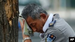 2023 年 7 月 3 日，在北京是炎热的一天。一位脖子上挂着电风扇的保安擦着汗。根据美国缅因大学气候再分析项目科学家的说法，周一和周二是非官方人类记录中最热的两天，整个地球都闷热难耐。 （美联社图片）