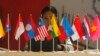 FILE - A woman sits in front of flags of the Association of South East Asian Nations (ASEAN).