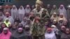  This undated image taken from video distributed Sunday, Aug. 14, 2016, shows an alleged Boko Haram soldier standing in front of a group of girls alleged to be some of the 276 abducted Chibok schoolgirls held since April 2014, in an unknown location.