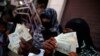 FILE - Women display paper currency after they received it in the form of assistance from the U.N. Children's Agency UNICEF, in Sana'a, Yemen, Nov. 14, 2015. 