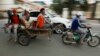 A Cambodian worker, third from left, views his mobile phone on a motor cart forwarding to work, in Phnom Penh, Cambodia, Tuesday, Aug. 11, 2015. Mobile phones are more popular than desktop computers in Cambodia. (AP Photo/Heng Sinith)