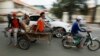 A Cambodian worker, third from left, views his mobile phone on a motor cart forwarding to work, in Phnom Penh, Cambodia, Tuesday, Aug. 11, 2015. Mobile phones are more popular than desktop computers in Cambodia. (AP Photo/Heng Sinith)