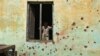 An Indian boy prepares to climb out the window of a house, the walls of which were damaged in mortar shell attack at Jora Farm village, in Ranbir Singh Pura, south of Jammu, India, Feb. 9, 2015. 