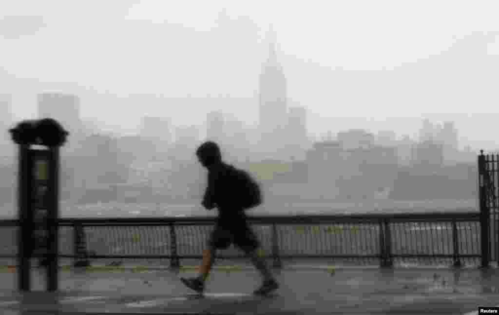 A man walks into the wind across the Hudson River from the skyline of New York in Hoboken, New Jersey, October 29, 2012.