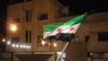 A handout picture released by the Syrian opposition's Shaam News Network shows a Syrian protester waving a pre-Baath Syrian flag during an anti-regime demonstration in Dael in the southern Daraa province late on April 12, 2012.