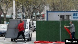 中国官方宣布，新冠疫情得到控制。但是，这一历史性灾难带来的后果正在显现。图为戴着口罩的工人正在拆除武汉街头的障碍物。（2020年3月21日资料照）
